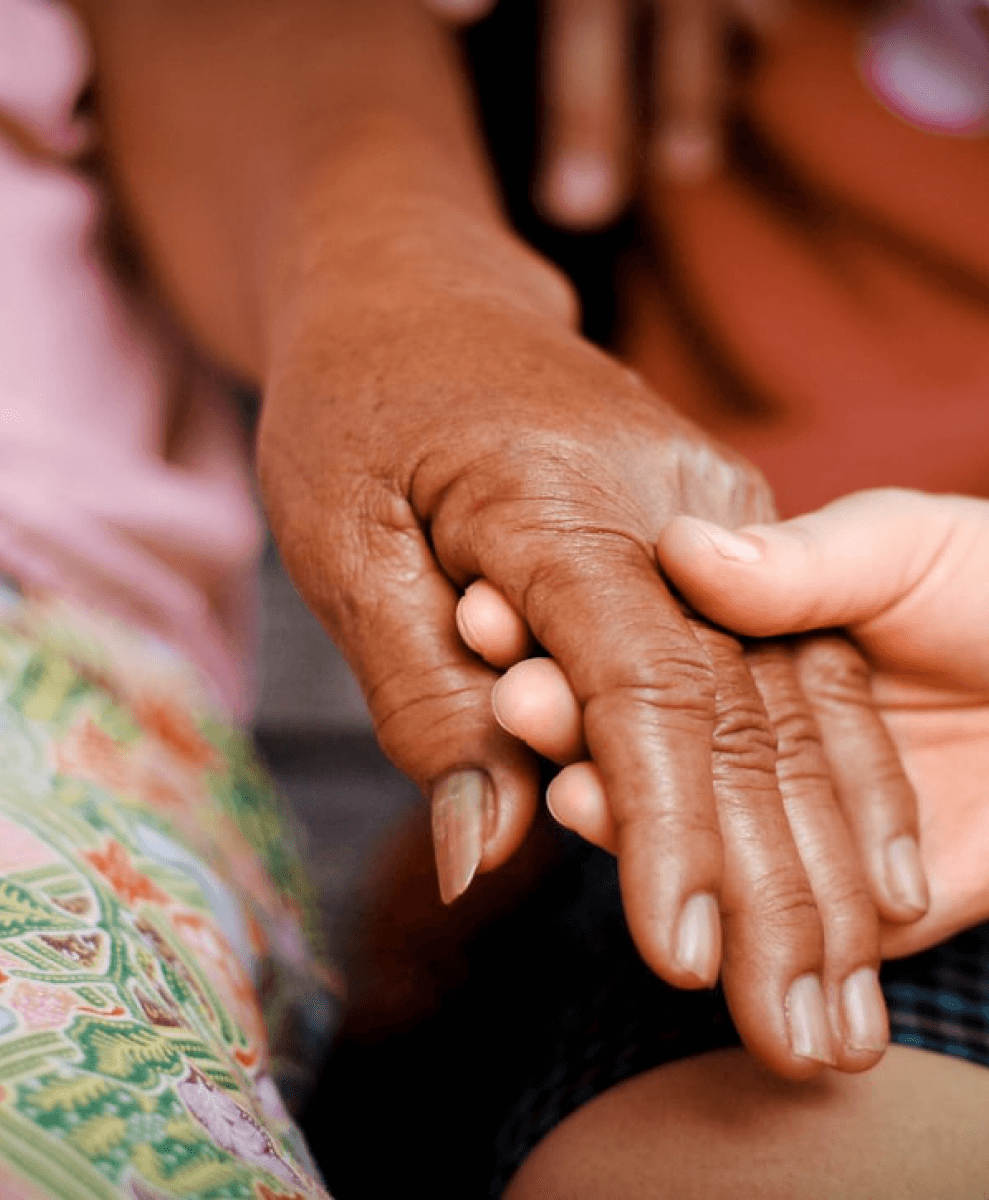 Cuidadora segurando mãos de paciente idoso com afeto e respeito